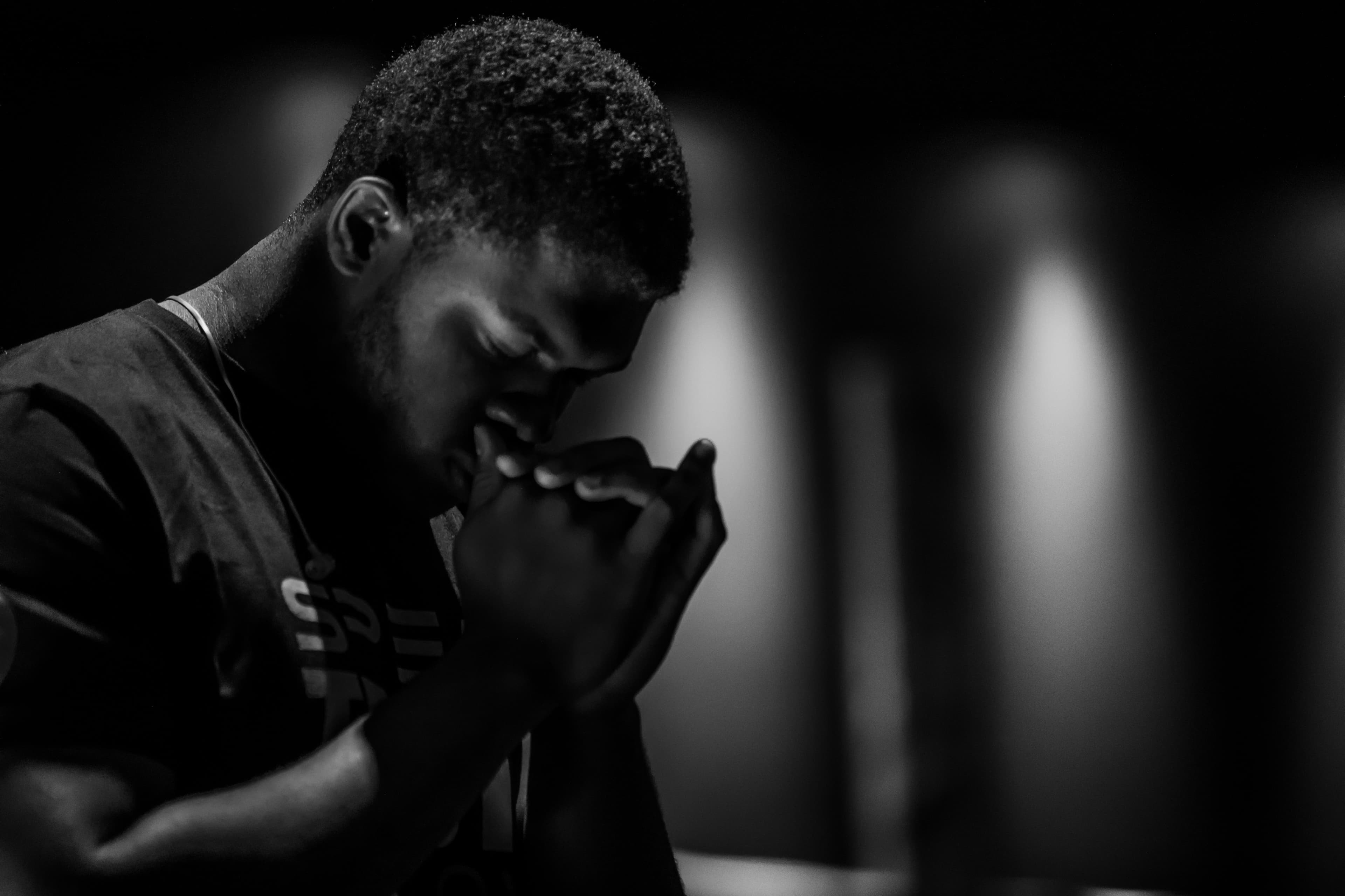 Young man praying quietly with a Bible.
